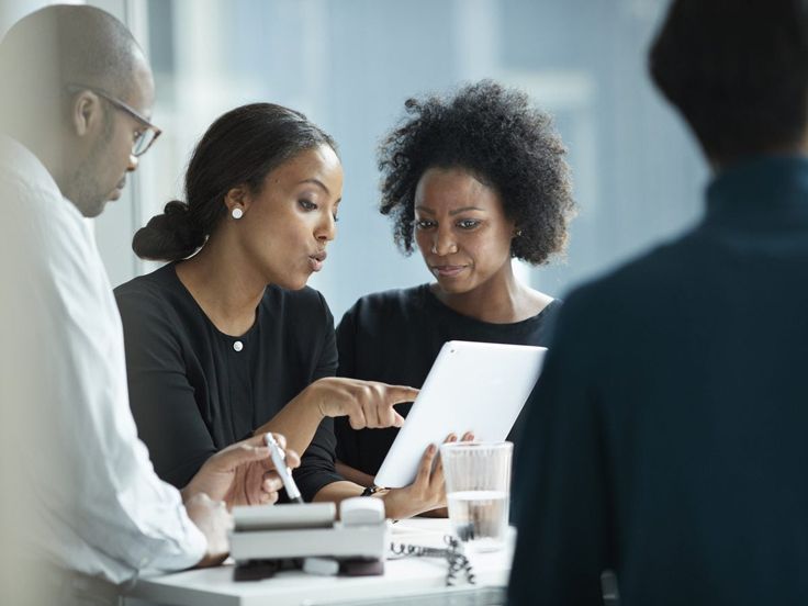 People gathered around a table reviewing a laptop and printed materials